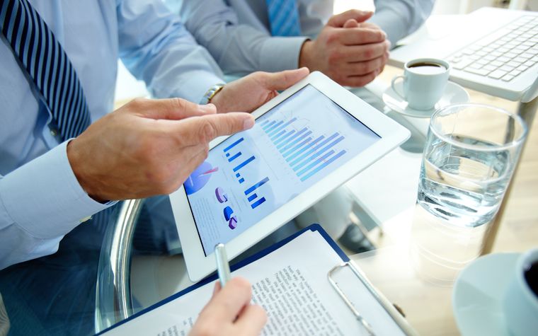Profissionais analisando gráficos financeiros em um tablet